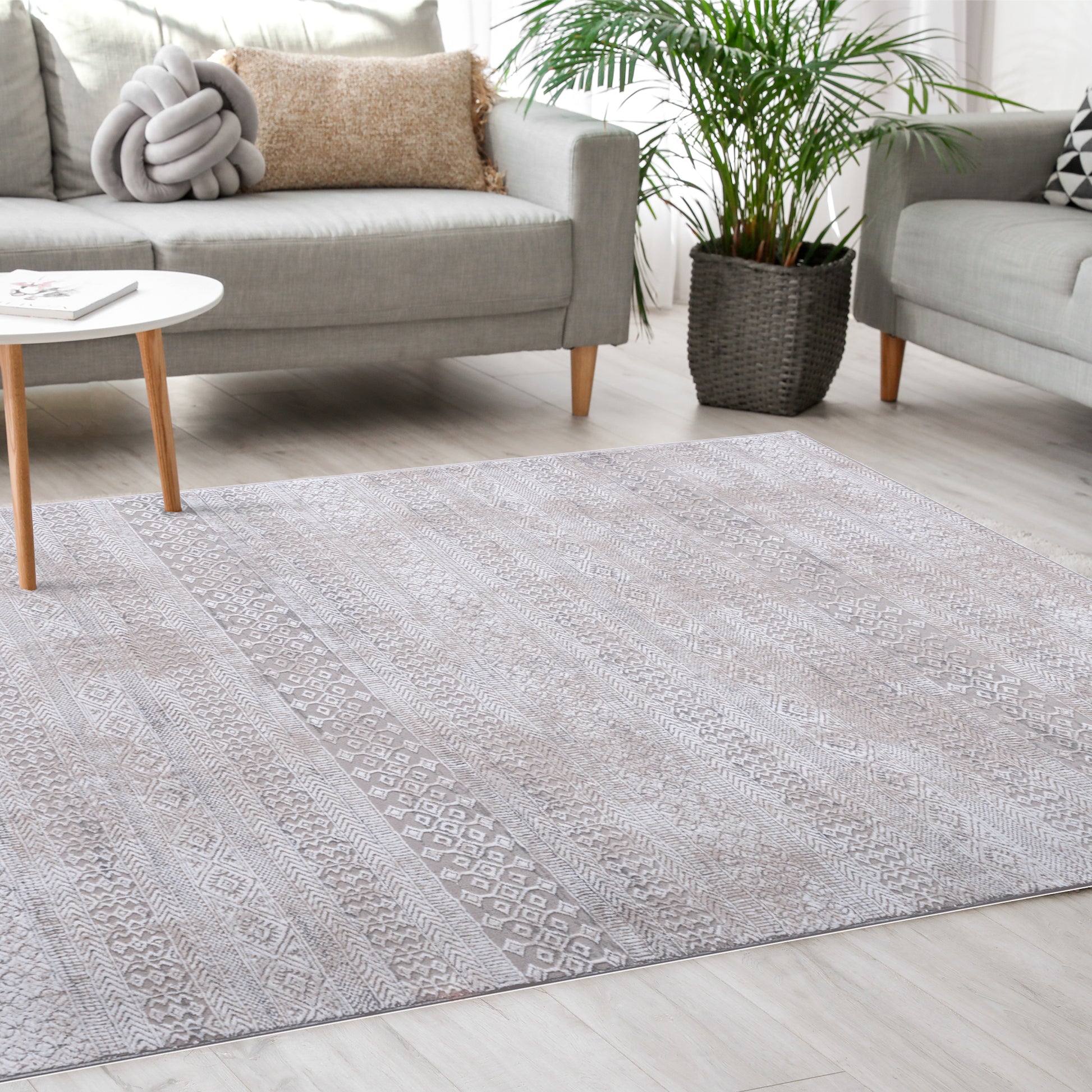 Tribal Ivory Rug in a bright Scandinavian living room along with minimalist grey sofas, modern white coffee table, pillows and plant