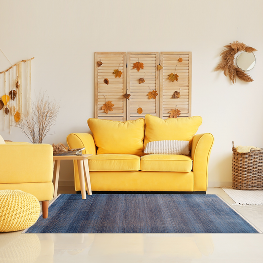 Bright autumn boho living room with yellow sofas, rattan baskets and wall decor, wooden coffee table and Mystic Navy Rug
